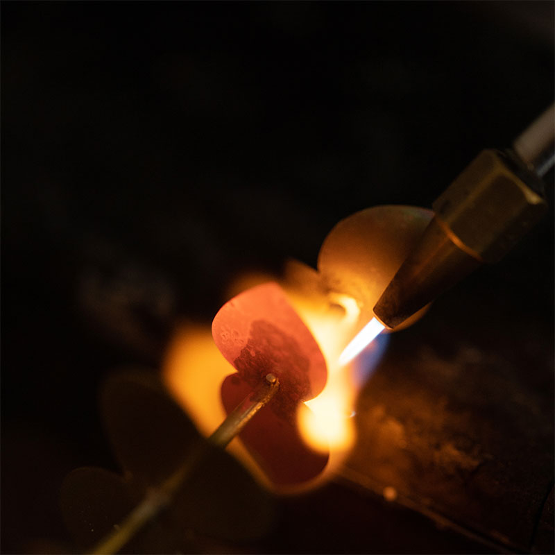 Feuilles en laiton rougies par la flamme du chalumeau pendant le brasage, dans l'atelier Les Aubépines